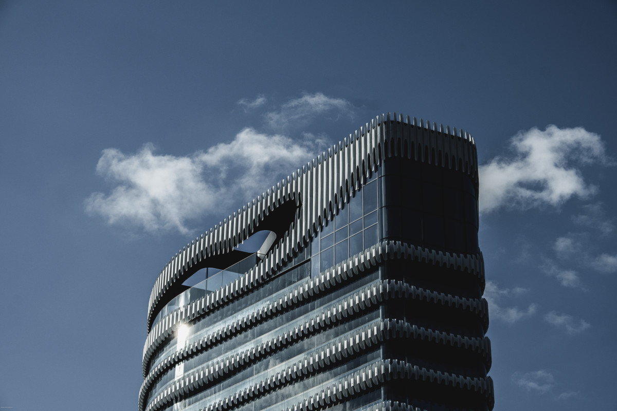 Hochhaus-Spitze von „The Zipper“ in Düsseldorf vor leicht bewölktem Himmel