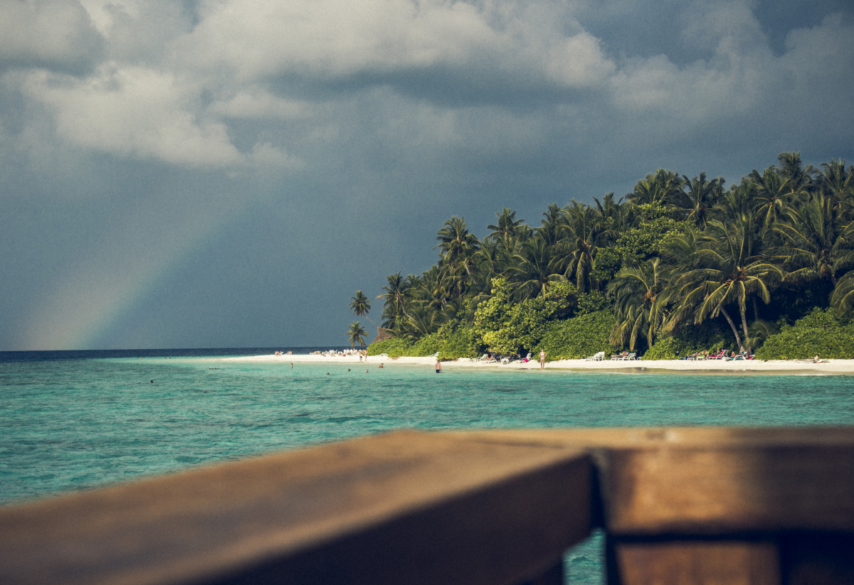 Südseeinsel mit Palmen im Meer mit Regenbogen