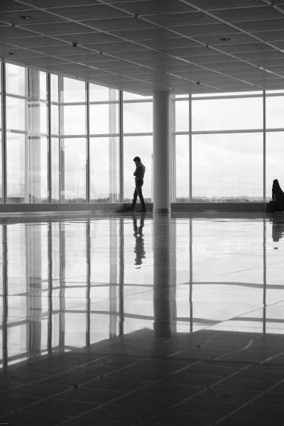 Silhouette eines Mannes in gläserner Flughafen-Wartehalle