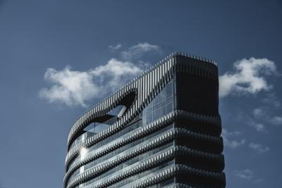 Hochhaus-Spitze von „The Zipper“ in Düsseldorf vor leicht bewölktem Himmel